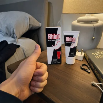 Verpackung und Tube der Rhino Long Power Creme auf einem Nachttisch neben Lampe und Buch