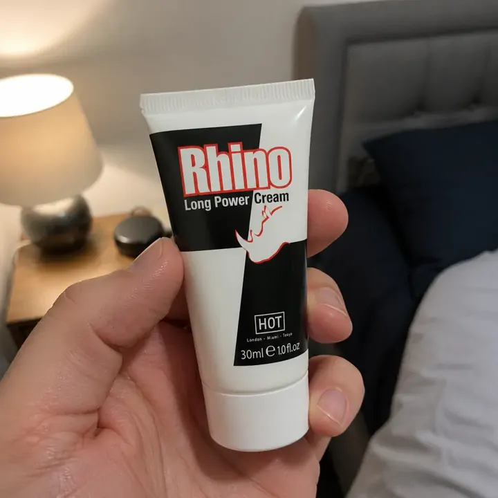 The 30 ml Rhino Long Power Cream tube held in one hand under a bedside lamp